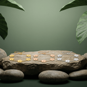 Flower Charm Bracelet displayed on a stone with greenery, showcasing elegant floral jewelry for women.