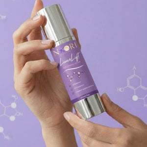 Person holding Luna Lift Facial Serum bottle against a purple background with molecular graphics.